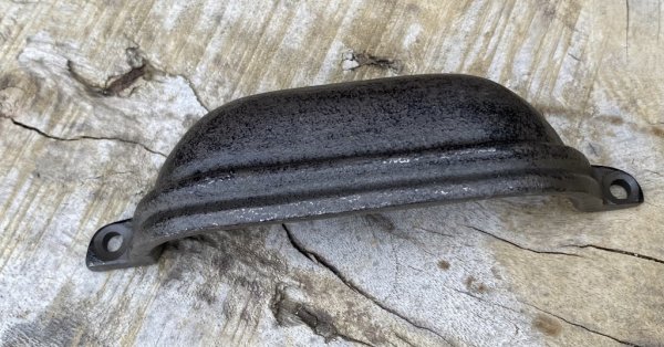 Skålformat handtag i järn. Djupare modell med bra grepp. Går i en ruffig brun nyans och har ett diskret rand mönster framtill. M