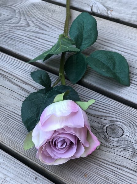 Vacker lila ros med gröna blad. Välarbetad vacker konstgjord ros med hög verklighets trogen känsla. Lika vacker ensam som i en b