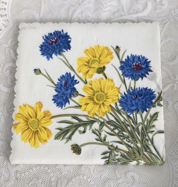 Sommar servetter med motiv av blåklint och gula sommar blommor på vit bas. Dekorerade med en lätt vågad ytterkant. 34cm * 34cm