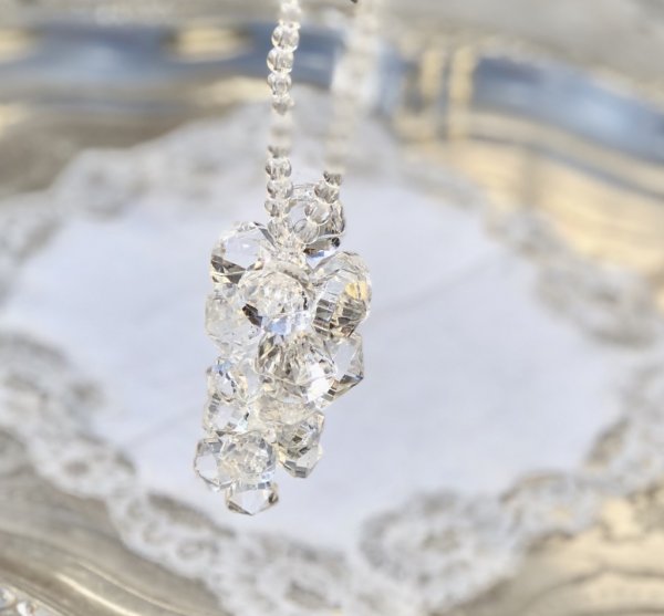 Vackert dekorations hänge med klara diamant formade prismor trädda på tråd. Prismorna är formade som en klase med vackert fallS