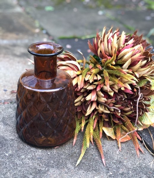 Vacker flaska / vas i glas. Brun färgad med gammeldags retro mönster runt om. För blommor eller enbart vacker dekoration. Höjd: