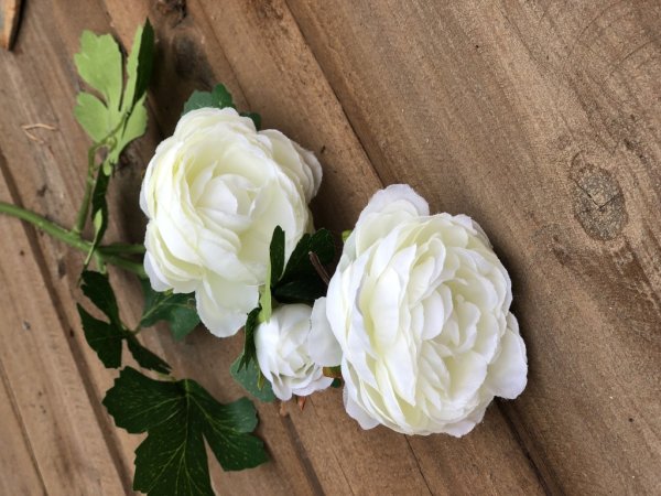 Vacker ranunkel blomma med gröna blad. Välarbetade i verklighetstrogen konstgjord modell. Går i mjuka nyanser av rosa och cream
