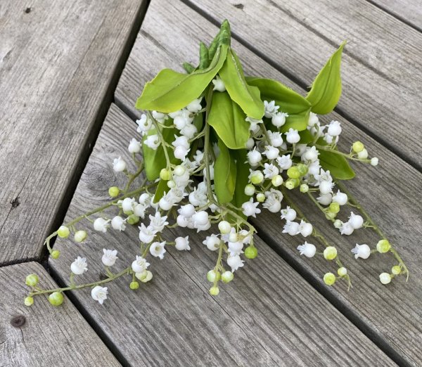 Vacker vit vår bukett med Liljekonvaljer i modell med fler blommor och gröna blad. Verklighetstrogna konstblomma välarbetad des