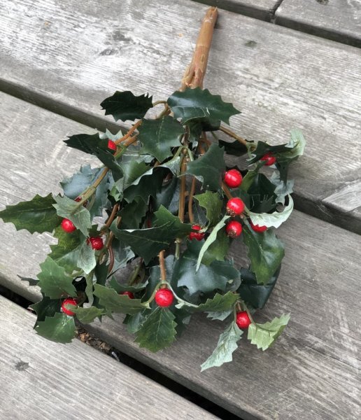 Järnek om flera kvistar gröna blad och röda bär. Välarbetad och detaljrik i verklighetstrogen konstgjord modell. Att pynta och