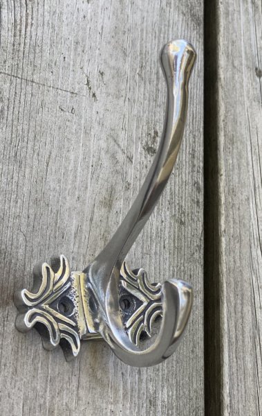 Klassisk elegant silver färgad  krok i vacker design. Med två hängare och vackert mönster på rygg plattan.   Höjd: ca 10cm Bredd