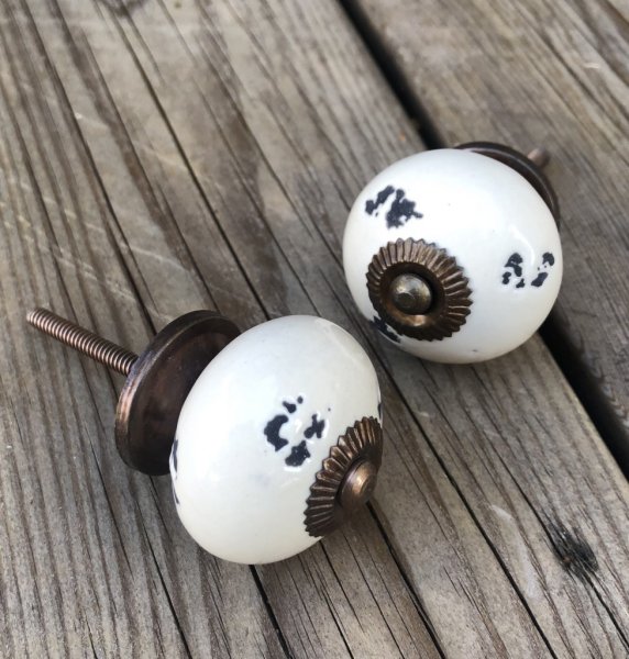 Lätt cream vit porslinsknopp med fabriks skavda/ruffiga inslag. Stommen går i en antik guld färgad nyans. Längd: ca 8cm Bredd: