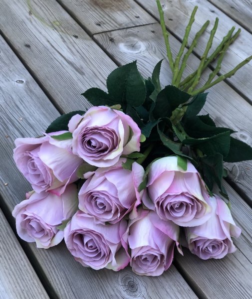 Vacker lila ros med gröna blad. Välarbetad vacker konstgjord ros med hög verklighets trogen känsla. Lika vacker ensam som i en b