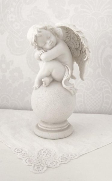 Vit ängel sittande på klot ansikte vänster