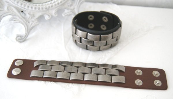 Brett läder armband med rundade nitar. Ställbart tryckknapps stängning i två lägen. Finns i två nyanser