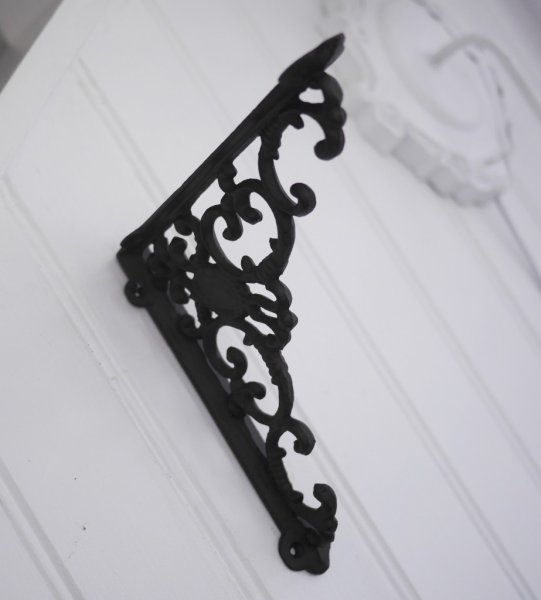 Konsol till tex hylla i smide mörk antik brun med detaljrikt utformning. Passar lika bra inne som ute. Höjd: ca 19,5 cm Dju