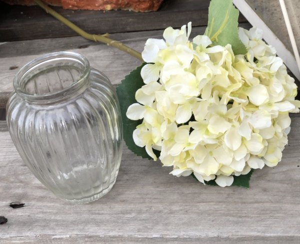 Hortensia i vit nyanser och gröna blad. Välarbetad och verklighetstrogen konstblomma. I kvist/gren modell om en blomma omgiven a