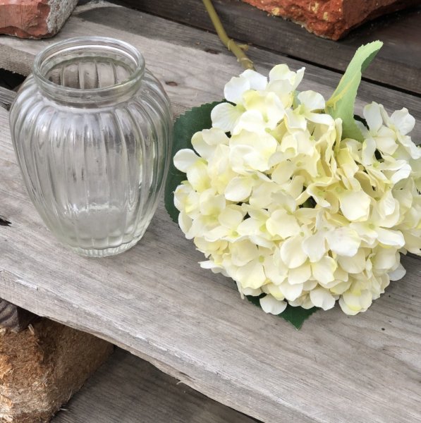 Hortensia i vit nyanser och gröna blad. Välarbetad och verklighetstrogen konstblomma. I kvist/gren modell om en blomma omgiven a