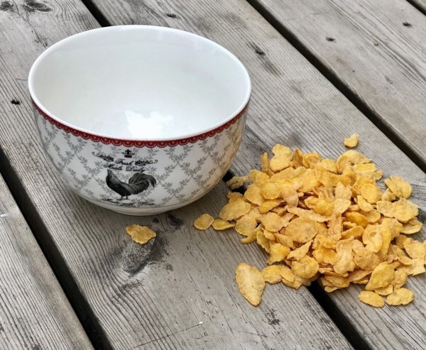 Vacker vit frukostskål i porslin. Dekorerad med grått spets liknande mönster en röd bord och en tupp. Från Miljögården  Mäter 12