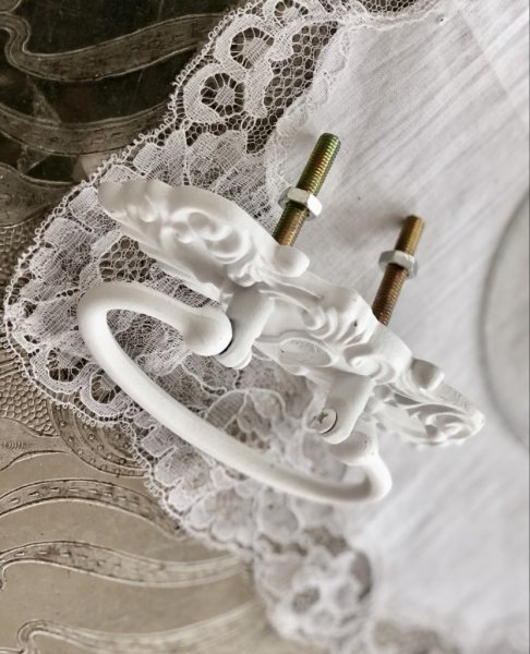 Vackert och detaljfullt handtag i gammeldags modell. I vit målad metall. Passande som handtag eller knopp på lådor skåp eller li