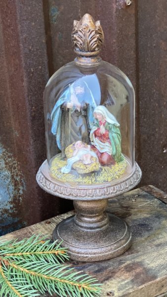 Vacker julkrubba med Josef, Maria och Jesus barnet. Under en glaskupa som står på ett vackert dekorerat fat på fot. Kupan sitter