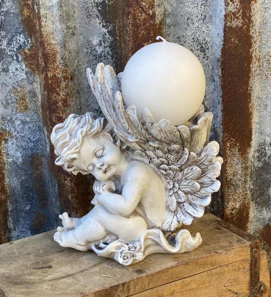 Vacker grå ängel som sitter ner och har stora vingar. På toppen av vingarna är det en avsats där man kan ställa ett ljus eller e