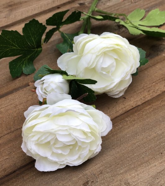 Vacker ranunkel blomma med gröna blad. Välarbetade i verklighetstrogen konstgjord modell. Går i mjuka nyanser av rosa och cream
