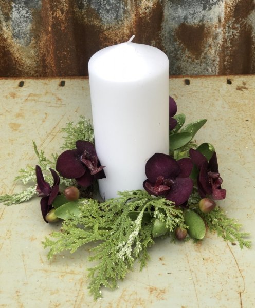 Vacker ljusmanschett / mindre krans med lila orkidéer och gröna inslag. Lika fin runt ljuset det större block/cylinder ljuset so