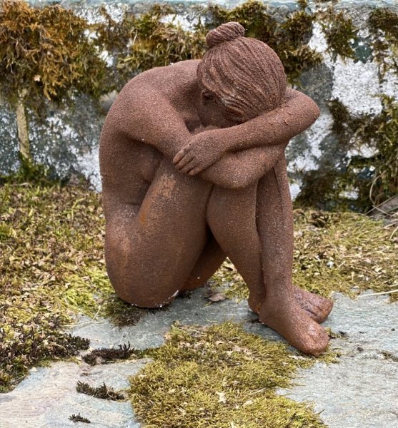 Aura rostig staty/figur av en kvinna i rost som sitter ihop kurad. Detaljrik och välarbetad. Ruffigt rostig modell. Höjd: ca 15