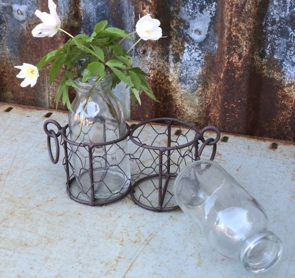 Glas vaser / flaskor som står i en nätad rost brun korg med ring formade handtag. Finns om två modeller -Två flaskor -Tre flasko
