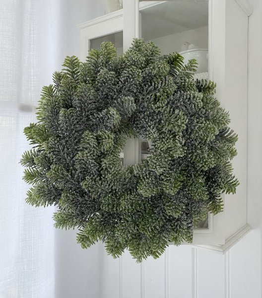 Vinter vacker grön krans av granris pudrad med snö. Elegant och verklighets trogen konstgjord krans på frigolit bas. Passande at