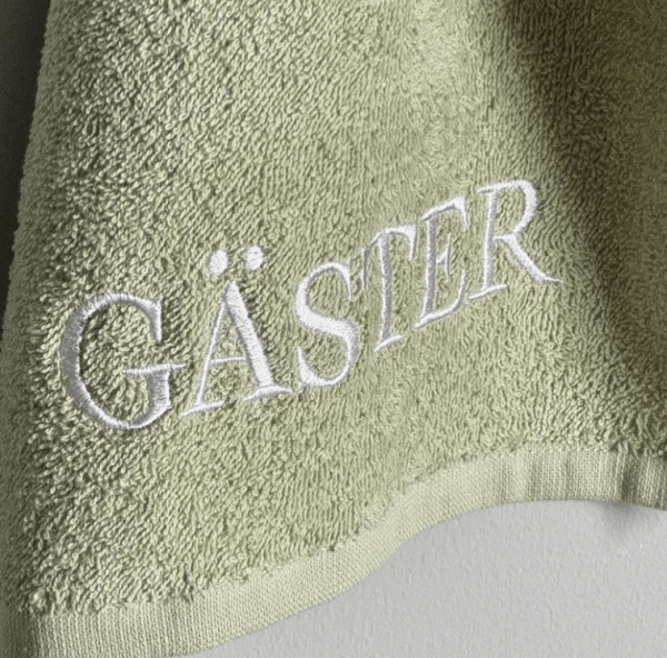 Grön GÄSTER handduk med broderad text