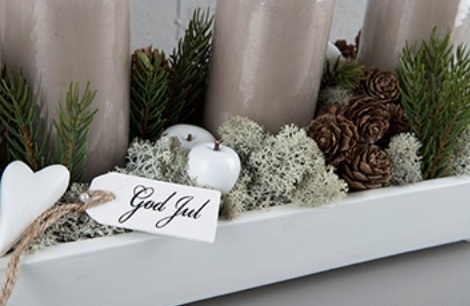 Liten vit trä skylt på snöre med text God Jul på en sida. Finns med
