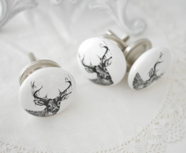 Vit porslins knopp med motiv i svart av en hjort / ren med horn. Med silverfärgad metall stomme samt krage. I greppvänlig modell