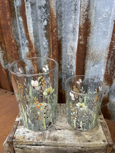 Vacker ljuslykta till lika vas med blommor och fjärilar