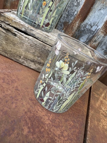 Vacker ljuslykta till lika vas med blommor och fjärilar