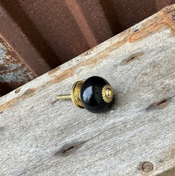 Svart rund mindre knopp med guld stomme 