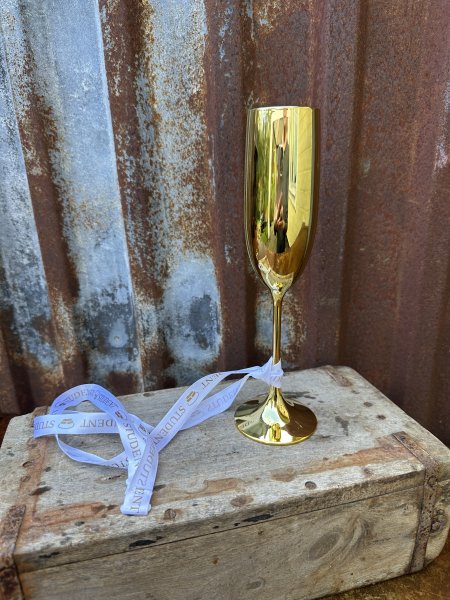 Glas student i guld på fot med band