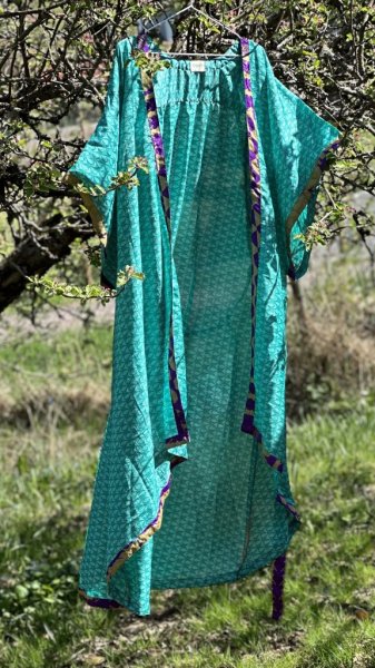 Vacker indisk kimono i turkosa nyanser. Tillverkad i vackert återvunnet tyg från Indiska kvinnors sarier säljes i förmån att stä