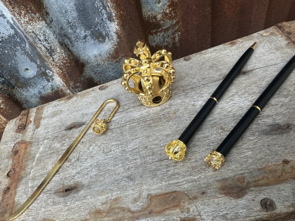 Krona i guld penna, pennvässare och bokmärke 