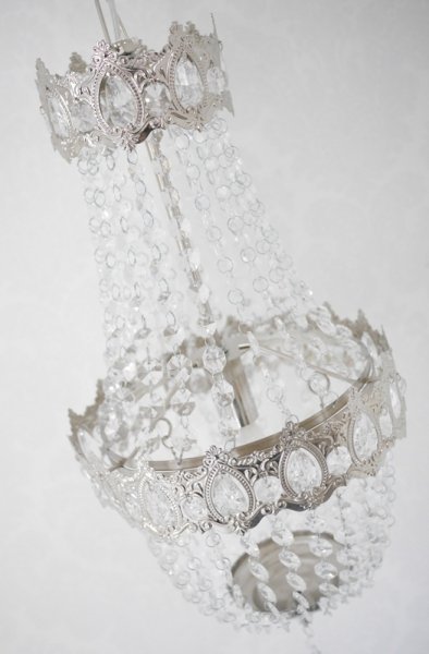 Vacker kristallkrona lampa i elegant modell med flera rader av prismor i olika variationer. Prismorna är i plast men ger sken av