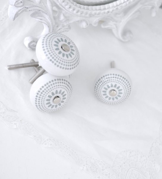 Vit rund porslins knopp med grått retro mönster likt en blomma. Med silver färgad metall stomme. I grepp vänlig modell.