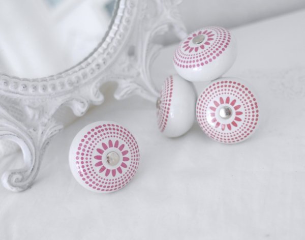Vit rund porslins knopp med rosa retro mönster likt en blomma. Med silver färgad metall stomme. I grepp vänlig modell.