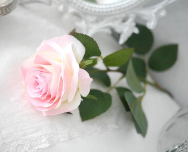 Vacker rosa verklighetstrogen konstblomma ros i utslagen vacker och romantisk modell med skaft och blad. Att dekorera med ensam