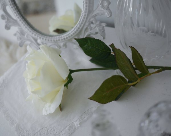 Cream vit ros i utslagen större modell med lång stjälk och gröna blad. Välarbetad vacker konstgjord blomma som gör sig lika bra
