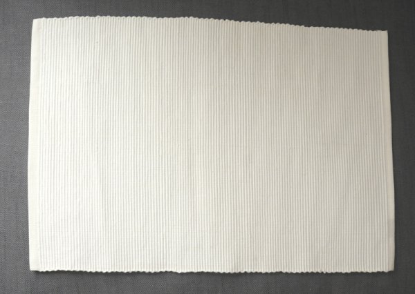 Vit bords tablett tillika duk i randigt sydd yta. Passande att duka på eller att ha som duk. I lite styvare material.